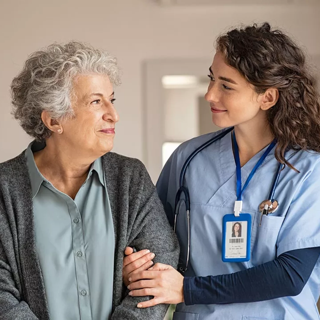 Nurse supporting woman, both smiling at each other