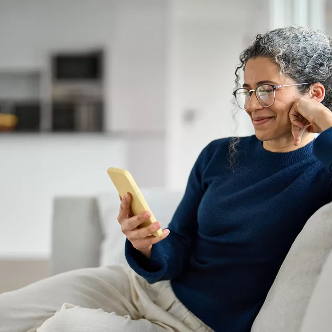 Woman sitting on the coach looking at her phone