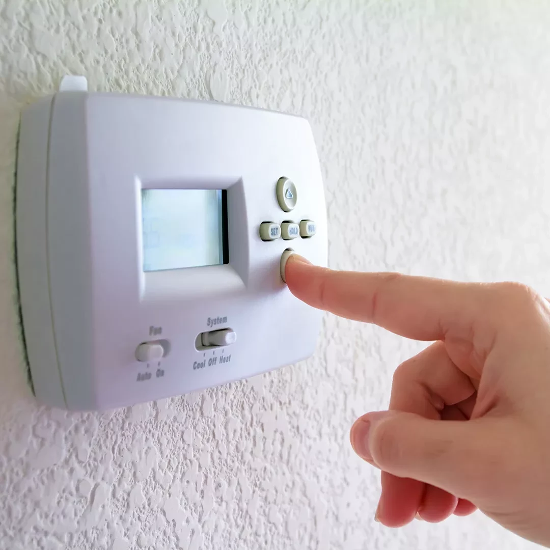 Person adjusting a thermostat with their finger