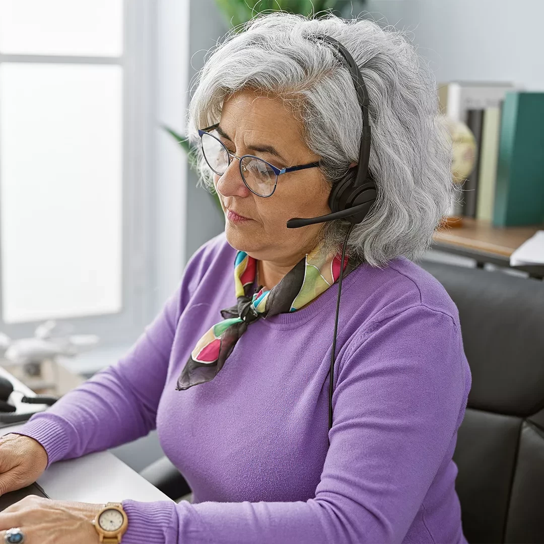 Older adult with a headset on while using a computer