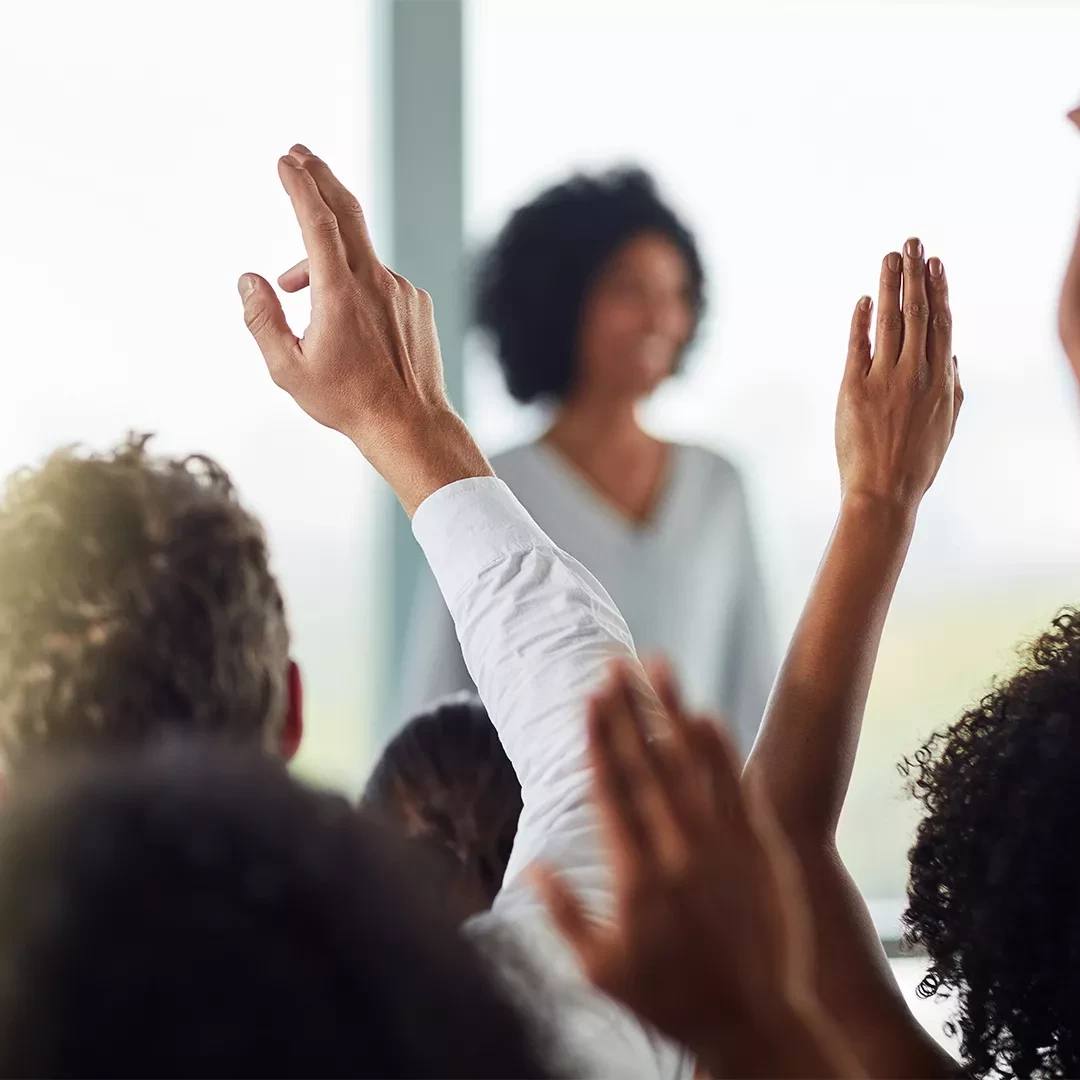 Speaker in from of audience raising their hands