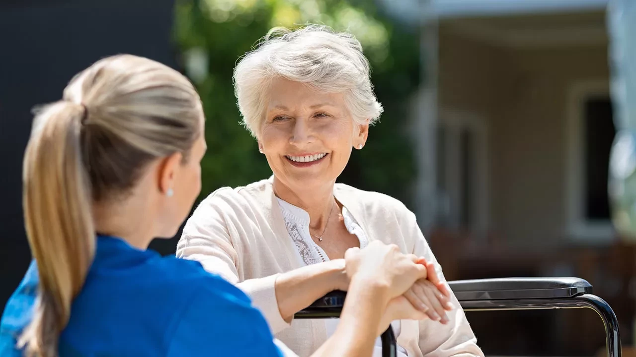 Older woman holding hands with a nurse